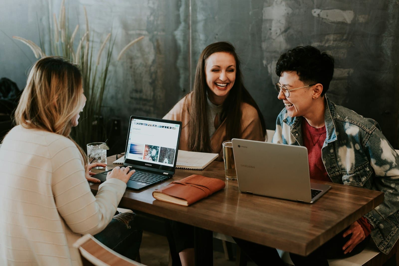 Team members collaborating at a table with laptops in a bright office